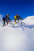 Two mountain bikers riding through deep snow, Serfaus, Tyrol, Austria