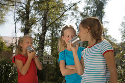 Four girls playing with a tin can phone, children's birthday party