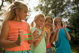 Four girls playing cat's cradle, children's birthday party