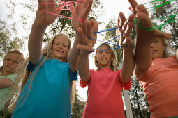 Three girls playing cat's cradle, children's birthday party