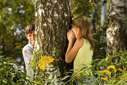 Girl and boy playing hide-and-seek, children's birthday party