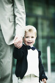Young boy holding father' s hand, smilling