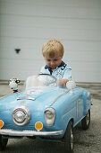 Young boy sitting in toy car