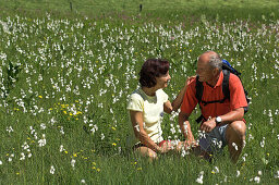 Couple sitting in a meadow full of flowers, Gleinkersee, Upper Austria, Austria