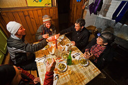 eine Gruppe Menschen in einer Berghütte prostet sich zu mit einem Glas Raki Schnaps, Demjanica Hütte, Pirin Gebirge, Bulgarien, Europa