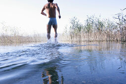 Male swimmer running into the water, Lake Staffelsee, Bavaria, Germany