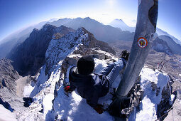 Man relaxing at the foot of the summit cross, Zugspitze, Bavaria, Germany
