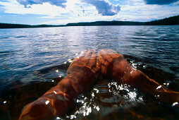 Man swimming in lake, close-up hands, Vastergotland, Sweden