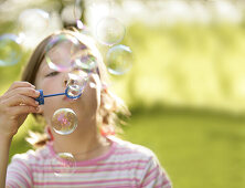 Girl (7-8 years) blowing soap bubbles
