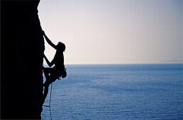 Kalymnos, Griechenland. Eine Frau klettert an einem senkrechten Felsen über dem Meer, Agäis, Europa, MR