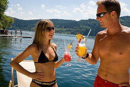 Couple relaxing drinking fruit cocktails, Millstaetter See, the deepest lake in Carinthia, Millstatt, Carinthia, Austria