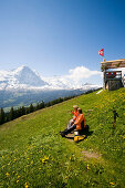 Hikers resting at Bussalp (1800 m), view to Eiger North Face (3970 m), Grindelwald, Bernese Oberland (highlands), Canton of Bern, Switzerland