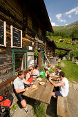 Group of hikers eating a Jause (snack) at Rastötzen Alm (1743 m), Bad Hofgastein, Gastein Valley, Salzburg, Austria