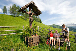 Couple resting at a crucifix and talking to a native man, Grossarl Valley, Salzburg, Austria