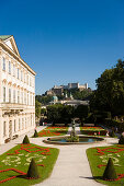 Tourists strolling through Mirabell garden, Hohensalzburg Fortress, largest, fully-preserved fortress in central Europe, in background, Salzburg, Salzburg, Austria