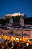 View over illuminated roof deck of restaurant Hotel Stein to old town with Salzburg Cathedral and  Hohensalzburg Fortress, largest, fully-preserved fortress in central Europe, in the evening, Salzburg, Salzburg, Austria, Since 1996 historic centre of the 