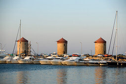 View over Mandraki harbour (translated literally: fold) with anchoring ships to windmills on mole, Rhodes Town, Rhodes, Greece