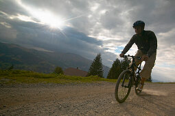 Mountainbiker on dirty road valley Simmental, Wistaetthorn (2362m) in background, Lenk, Bernese Oberland, Canton Bern, Switzerland, MR