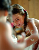 Kinderwellness, Kinder haben Spaß beim bemalen mit einer natürlichen Feuchtigkeitsmaske Quark, Honig, Öl),  Wellness Anwendung in einem Hotel, Deutschland