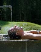Mann badet in einer Viehtränke, Simmental, Berner Alpen, Kanton Bern, Schweiz