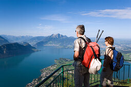 Mature adult couple at Kanzli vantage point on Rigi (1797 m, Queen of the Mountains) and looking over Lake Lucerne with Weggis, mount Bürgenstock and mount Pilatus (2132 M) in the background, Rigi Kaltbad, Canton of Schwyz, Switzerland