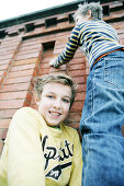 Boy giving friend a bunk-up over a wall