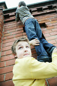 Two boys climbing over a wall