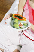 Close up of a young woman holding a plate of exotic fruits, Food