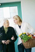 Young woman helps an elderly lady and carries the shopping