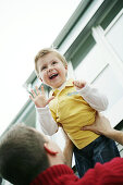 Father lifts son in the air, laughing