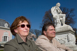 Mature couple sitting in front of Benrath castle, Dusseldorf, North Rhine-Westphalia, Germany