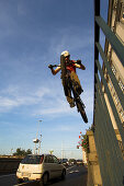 Junger Mann auf einem Trialbike springt an einem Tor vorbei, Linz, Oberösterreich, Österreich