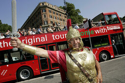 Mann im römischen Kostüm posiert für Touristen vor Besichtigungsbus beim Colosseum, Rom, Italien