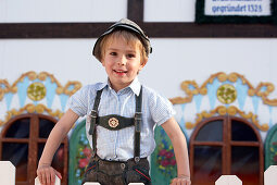 Boy (3-4 years) standing behind a fence