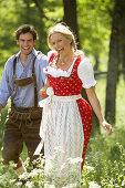 Couple running hand in hand over a meadow