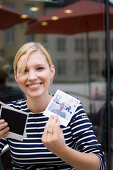 Junge Frau sitzt in einem Straßencafe und sieht sich Fotos an, Luxemburg