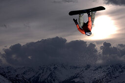 Snowboarder juming at sunset, See, Tyrol, Austria