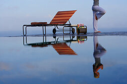 Young woman meditating at the edge of a swimming pool, near Uluwatu, Bali, Indonesia