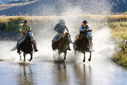 Cowgirl und Cowboys reiten in Bachbett, Wilder Westen, Oregon, USA