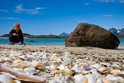 A child, girl collecting sea shells on the beach of Store Molla Island, Lofoten, Norway
