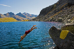 Young man jumping into lake Lago d'Orsino, Gotthard, Canton of Ticino, Switzerland