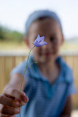 Girl presenting a single bell flower, Sylt island, Schleswig-Holstein, Germany
