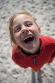 Girl on beach laughing at camera, Sylt island, Schleswig-Holstein, Germany
