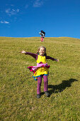 Girl running on farmland, grazing sheep, near Puponga, Golden Bay, northern coast of South Island, New Zealand