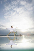 Couple practising yoga at Lake Starnberger, Muensing, Bavaria, Germany, MR