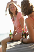 Zwei Frauen trinken Bier auf einem Holzsteg am Wörthsee, Bayern, Deutschland, MR