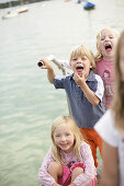 Children playing on the jetty, pulling faces, Woerthsee, Upper Bavaria, Bavaria, Germany