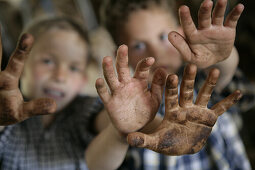 Two boys in the barn, showing dirty hands, Walchstadt, Upper Bavaria, Germany