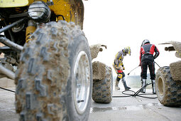 Two men, man being hosed down after riding quad, Suzuki Offroad Camp, Valencia, Spain