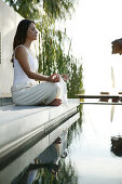 Frau beim Meditieren am Pool, Wellness, Entspannung, Sommer